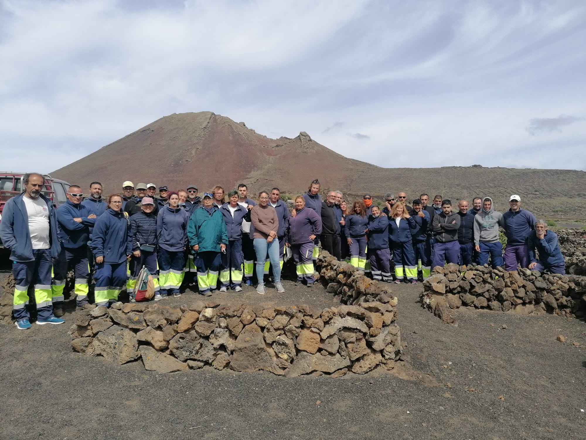 Gran grupo del equipo posando frente a un volcán en Lanzarote