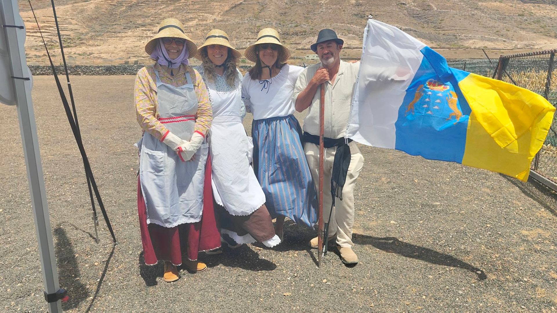 Compañeras y compañero del equipo vestidos con traje tradicional canario sosteniendo la bandera de Canarias