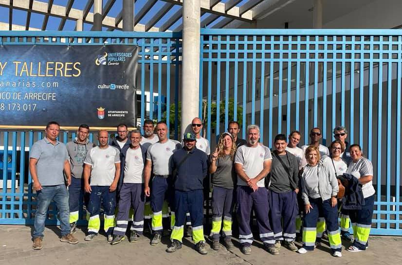 Equipo de trabajadores posando frente a las puertas azules de los talleres en Arrecife