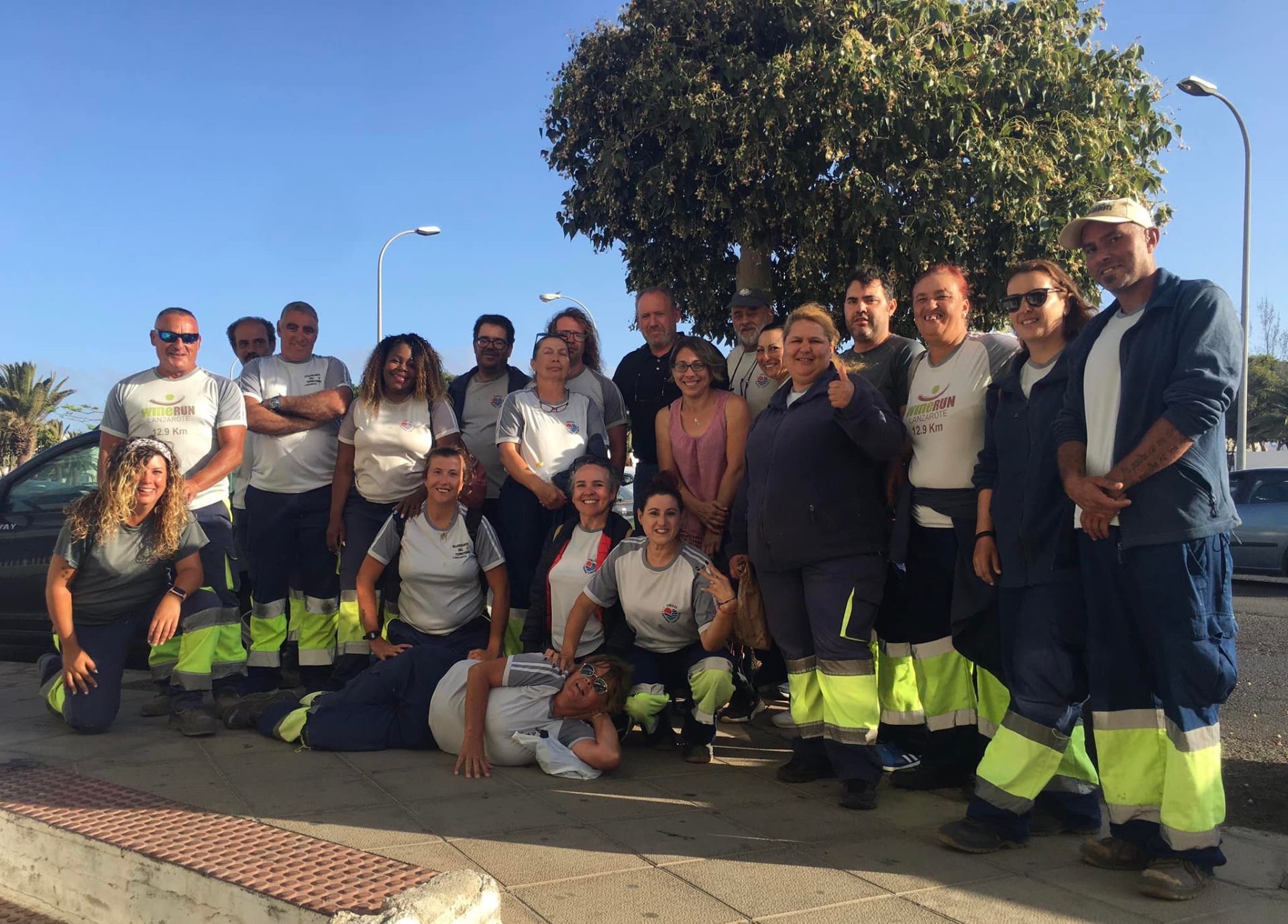Equipo sonriente posando bajo un árbol en una calle de Lanzarote