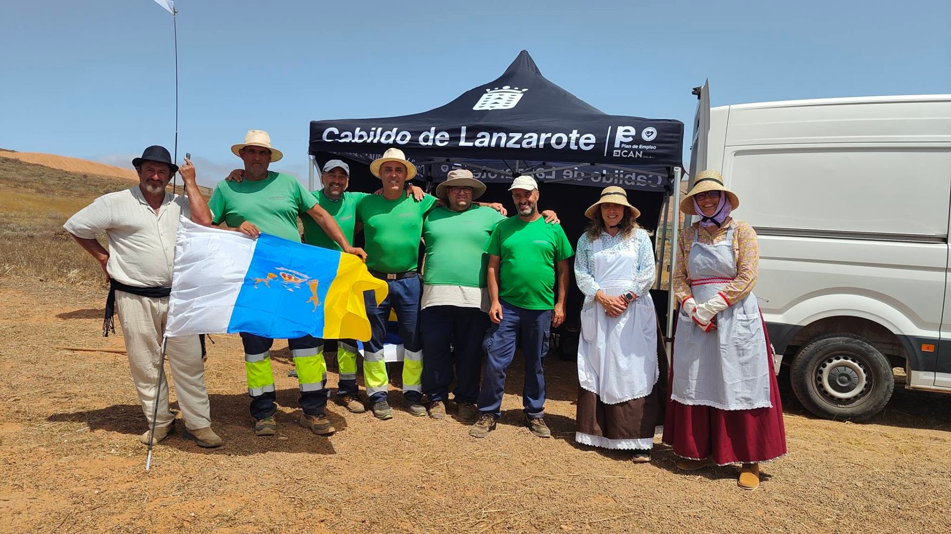 Equipo posando con la bandera de Canarias frente a una carpa del Cabildo de Lanzarote